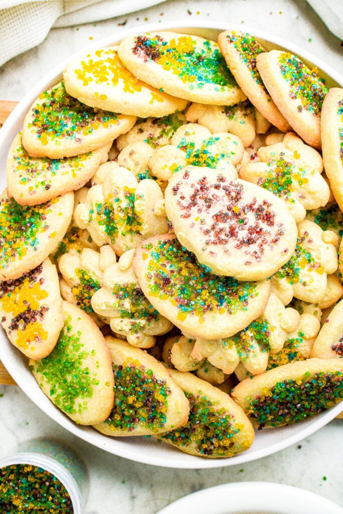Close up overhead photo of a round plate of vegan cookies shaped like Easter eggs and decorated with colored sugar