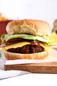 Head on view of a homemade vegan burger with dairy free cheese, lettuce, and rice paper bacon