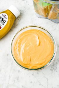Overhead photo of vegan cheddar cheese spread in a clear glass container
