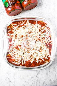 Overhead photo of a square baking dish with stuffed vegan pasta inside covered with a glass lid