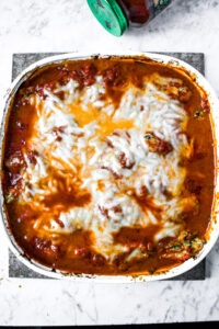 Overhead photo of a small baking dish with Vegan Baked Conchiglioni topped with marinara sauce and melted dairy-free cheese
