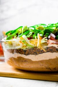Head on photo of a clear glass container with dairy-free 7-layer taco dip in it