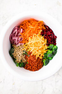 Overhead photo of a large mixing bowl filled with all the ingredients to make broccoli slaw