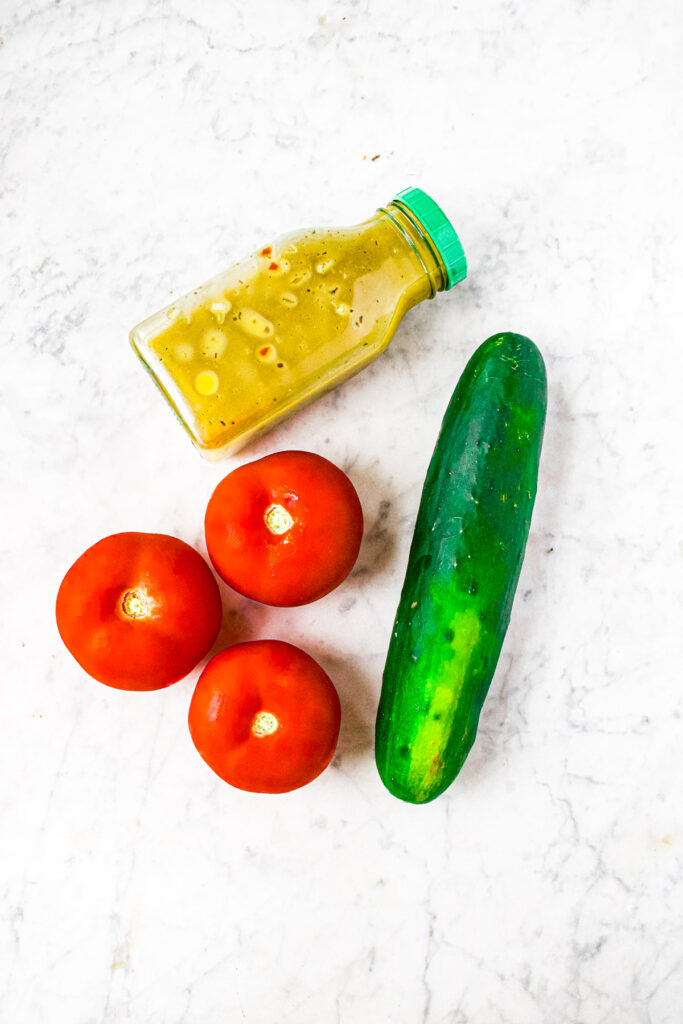 Overhead photo of the 3 ingredients you need to make easy cucumber tomato salad in Italian dressing