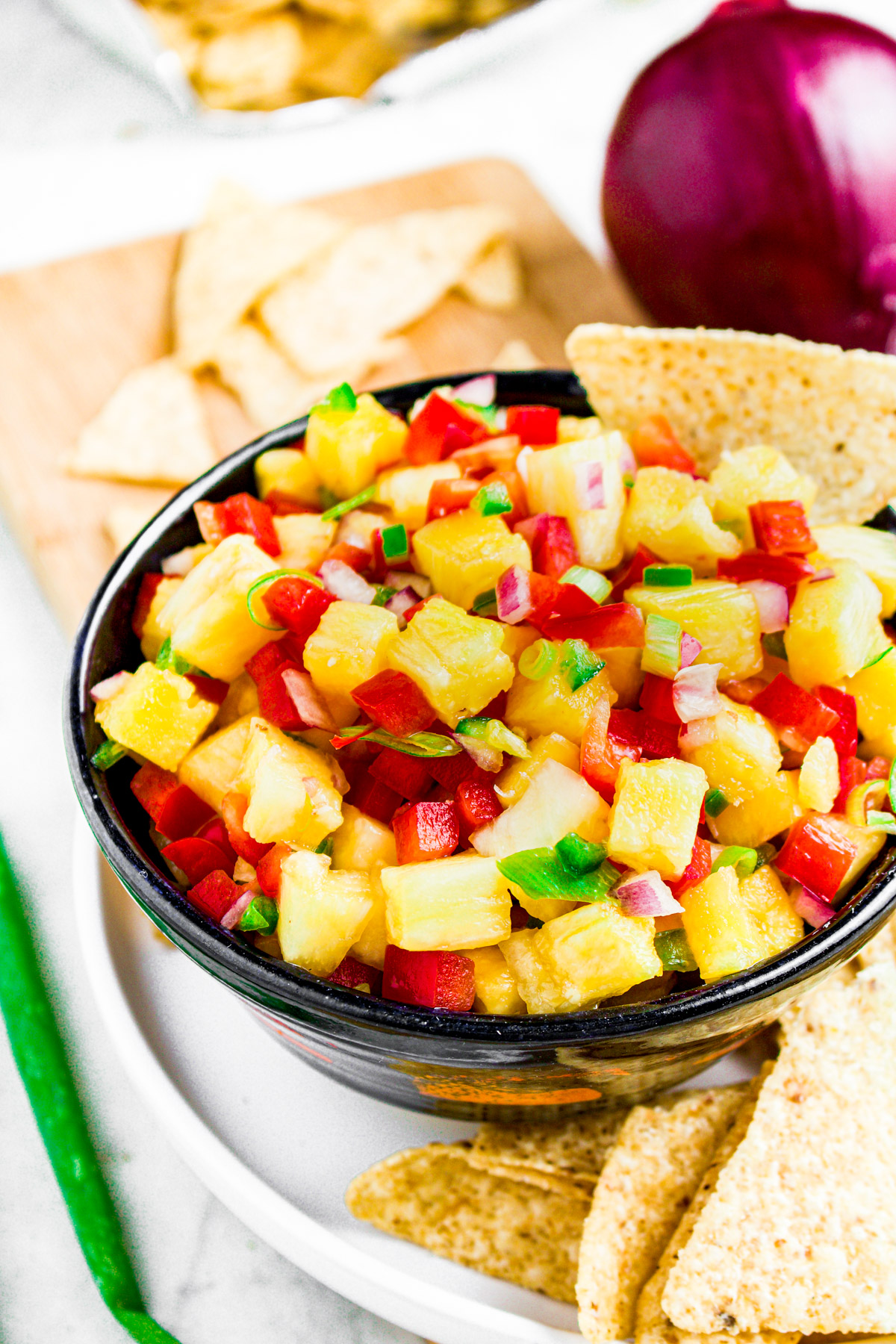Overhead photo of a small bowl of pineapple salsa surrounded by corn chips