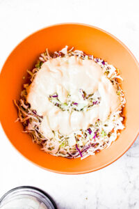 Overhead photo of a large bowl of coleslaw mix with healthy coleslaw dressing poured on top