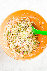 Overhead photo of a large mixing bowl filled with creamy sesame tahini slaw with a silicone spatula in it