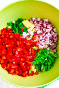 Overhead photo of a mixing bowl with all the ingredients to make pico de gallo in it before they're stirred.