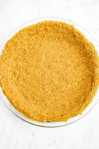 Overhead zoomed in photo of a no-bake graham cracker crust in a clear glass pie dish