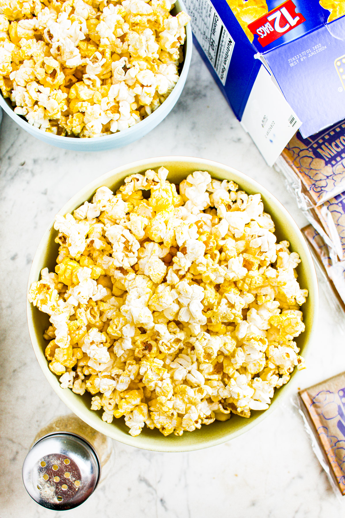 Overhead photo of two bowls of microwave popcorn with a blue box in the upper right corner