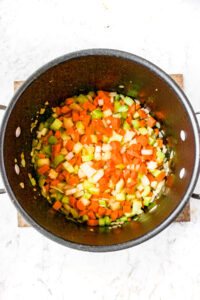 Overhead photo of carrots, celery, and onions sauteeing in a large soup pot