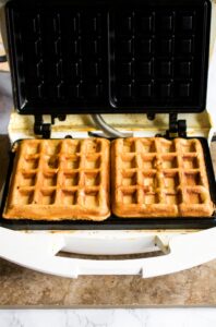 Overhead photo of healthy apple waffles cooking in a waffle maker