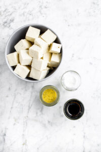 Overhead photo of the ingredients you need to make air fried tofu: cubed tofu, bouillon, cornstarch, and soy sauce
