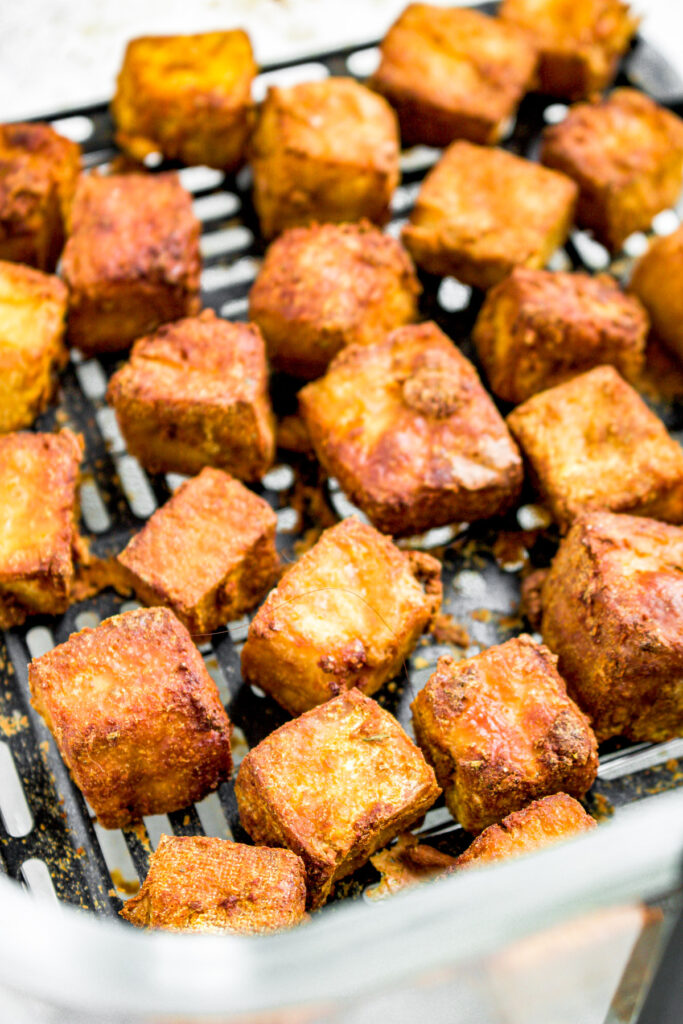 Overhead photo of an air fryer basket filled with crispy browned tofu cubes