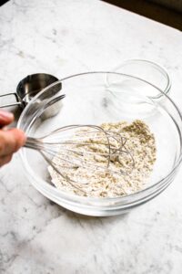 Overhead photo of a whisk mixing dry ingredients for vegan latkes