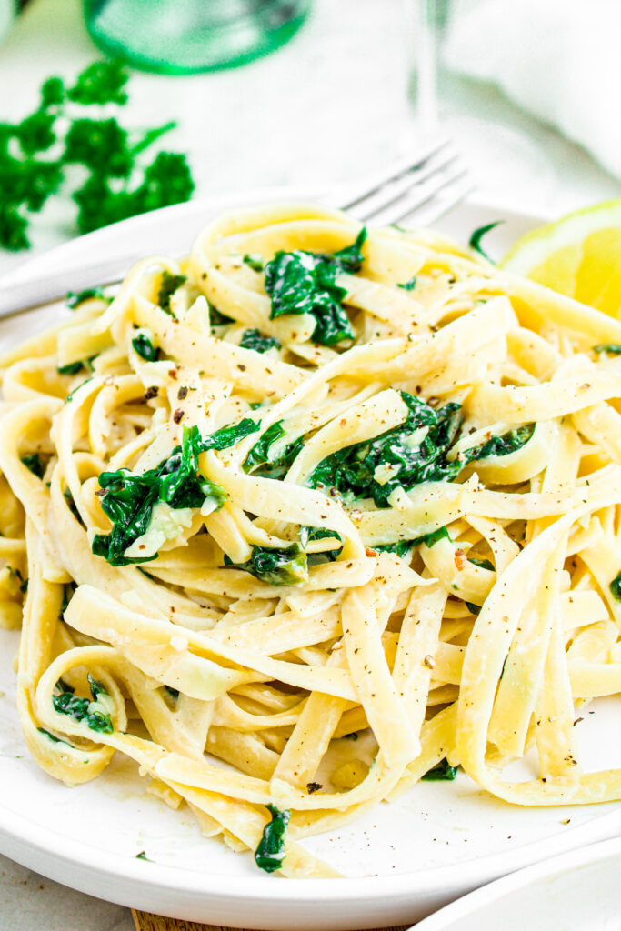 Close up overhead photo of a plate of creamy vegan lemon and spinach pasta
