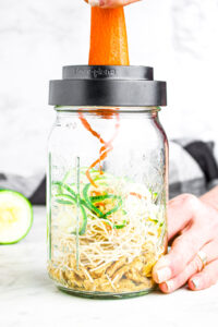 Overhead photo of a carrot being spiralized into a large mason jar