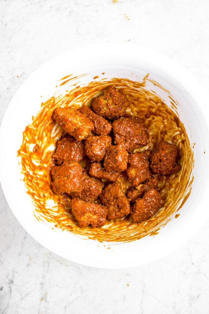 Overhead photo of a white mixing bowl with saucy meatless chicken wings in it