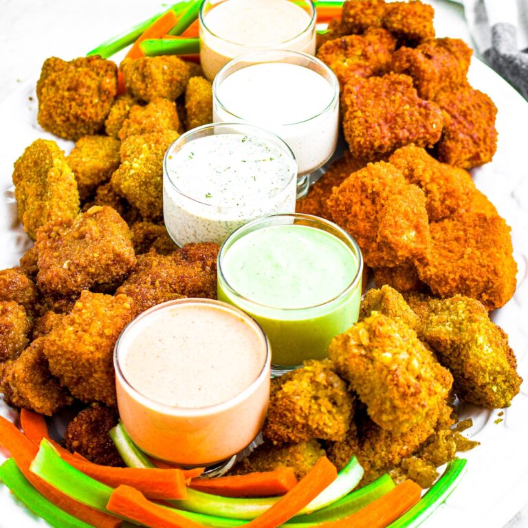 Head on close up photo of a large plate of vegan chicken wings and vegan ranch sauces
