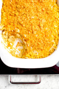 Overhead close up view of a rectangular white casserole dish of vegan baked macaroni and cheese sprinkled with Spicy Sweet Chili Doritos