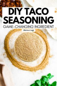 Overhead close up view of a clear glass open jar of homemade taco seasoning with text reading DIY taco seasoning game changing ingredient