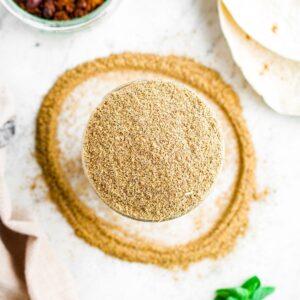 Overhead close up view of a clear glass open jar of homemade taco seasoning