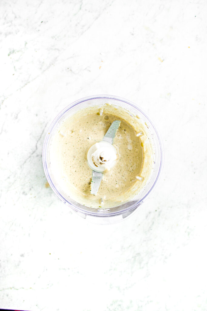 Overhead view of a creamy vegan ranch sauce made with silken tofu in a clear open food processor