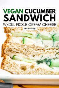 Head on view of a cucumber sandwich sliced in half and stacked on top of each other on a wood cutting board with text reading vegan cucumber sandwich with dill pickle cream cheese