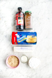 Overhead view of all the ingredients you need to make easy vegan cinnamon buns out of a tube of biscuits sitting on a grey marble counter top