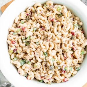 Overhead view of a round white bowl filled with vegan macaroni salad with colorful diced veggies