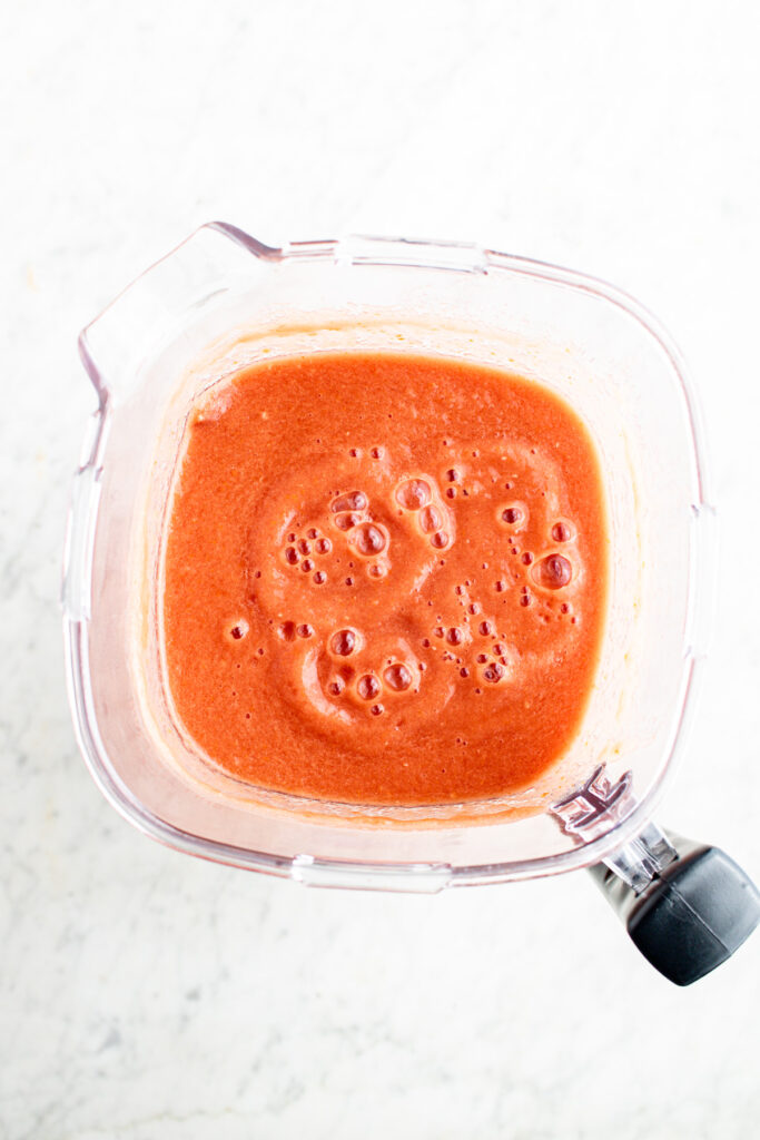 Overhead view of a large blender filled with tomato puree