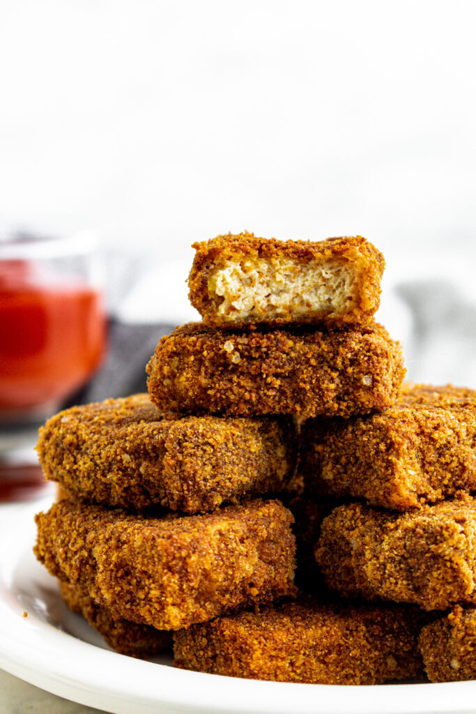 Head on view of a pile of vegan tofu nuggets with a bite taken out of the top one