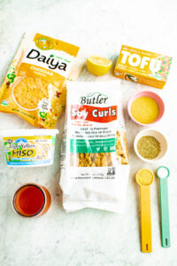An overhead view of all the ingredients you need to make vegan buffalo chicken dip laid out on a grey marble countertop