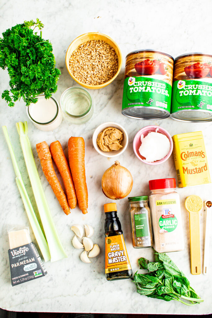 Overhead view of all the ingredients you need to make vegan TVP bolognese laid out on a grey marble countertop
