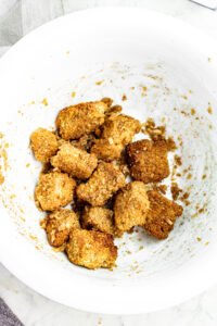 Overhead view of a round white bowl filled with just-sauced vegan garlic parmesan wings