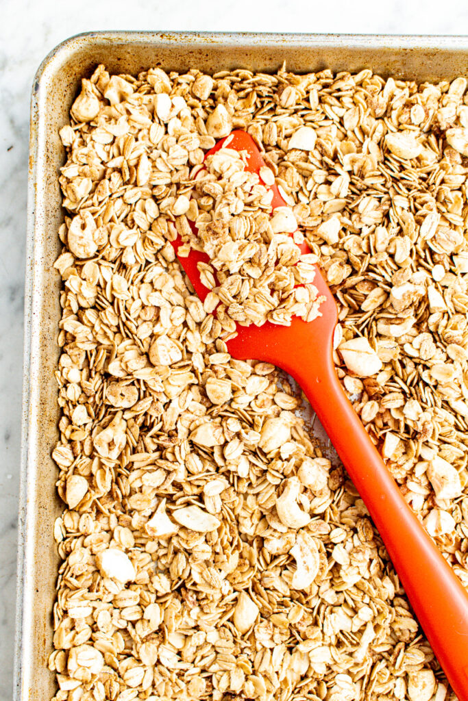 Close up overhead view of a red spatula with vegan granola piled on top and around it
