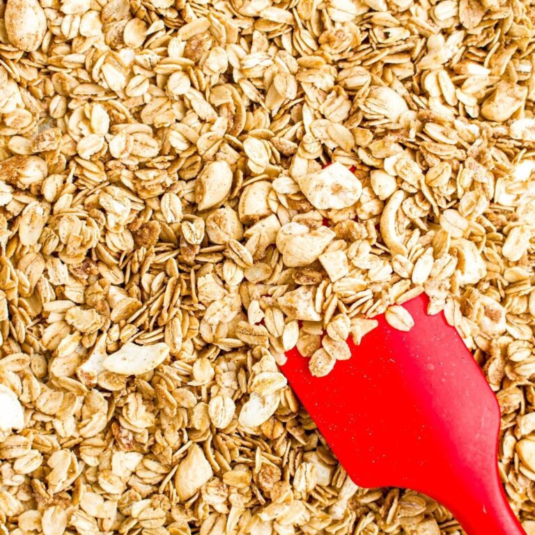 Close up overhead view of a red spatula pushing vegan granola
