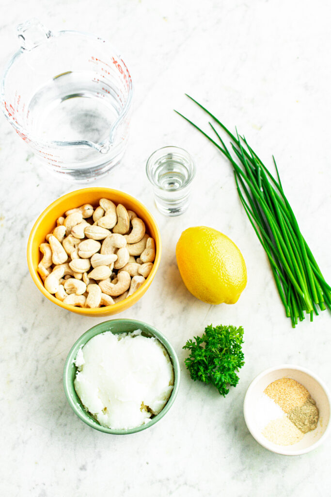 Overhead view of all the ingredients you need to make vegan Boursin cheese out of cashews laid out on a grey marble countertop