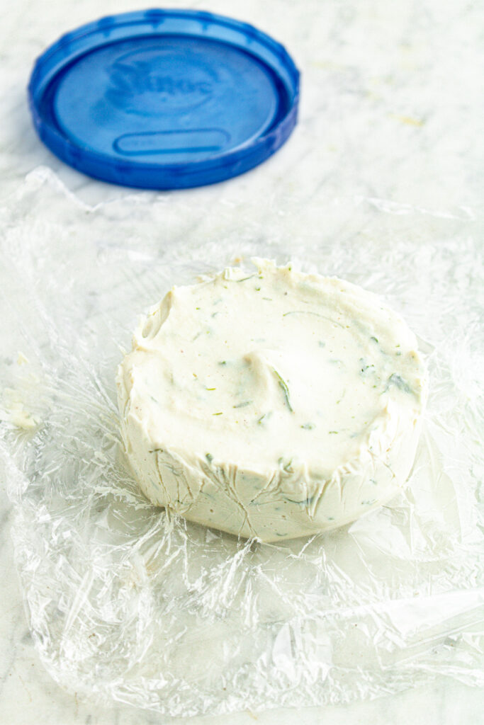 Overhead view of a cashew cheese wheel after setting and being pulled out by the plastic wrap