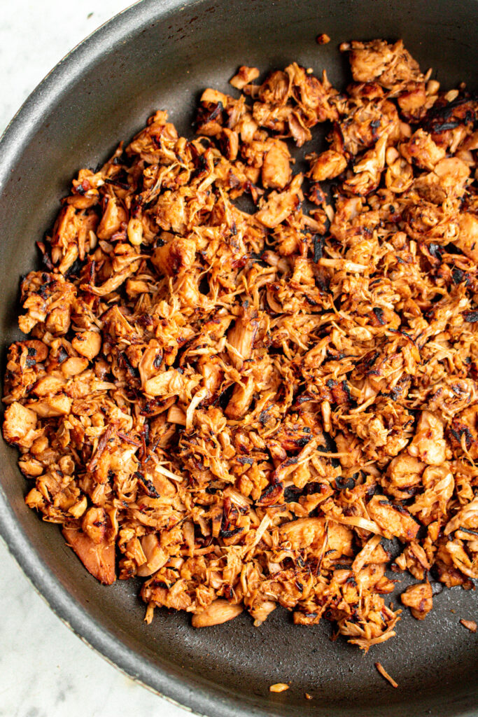 Overhead view of a pan with browned jackfruit pulled pork in it showing what the jackfruit looks like when ready to remove from heat